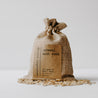 Herbal organic oatmeal bath soak in a burlap bag with some of the contents dumped out.