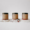 Herbal Epsom Bath Salts in amber jars. The bath salts are spilled out and there are eucalyptus leaves, chamomile flowers, lavender buds and rose petals